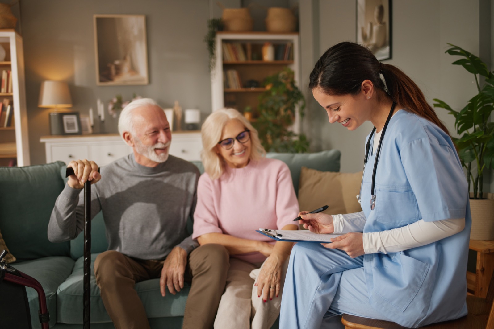 A nurse taking notes with an older couple in their living room